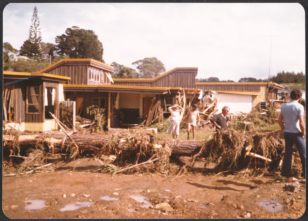 People standing outside damaged house