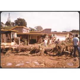 People standing outside damaged house